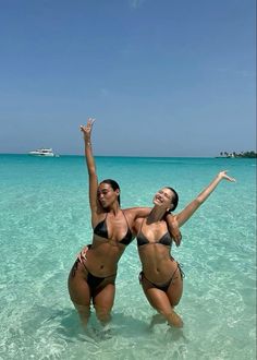 two women in bikinis are standing in the water