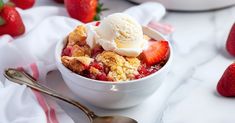 a bowl filled with ice cream and strawberries on top of a white tablecloth