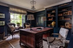 an office with blue walls and lots of bookshelves in the corner, along with two chairs