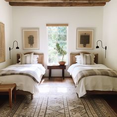 two beds in a room with white walls and wood beams on either side of the bed