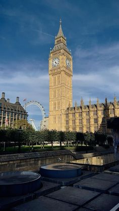 the big ben clock tower towering over the city of london, england with ferris wheel in the background