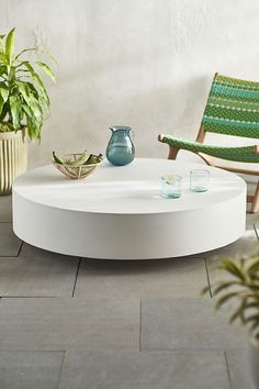 a white coffee table sitting on top of a tiled floor next to potted plants