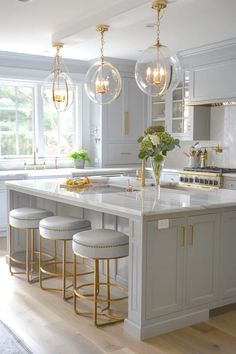 a large kitchen with marble counter tops and gold accents on the pendant lights over the island