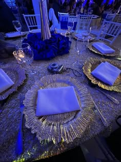 the table is set with silver plates and blue napkins