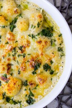 a white bowl filled with cheese and spinach covered in broccoli florets