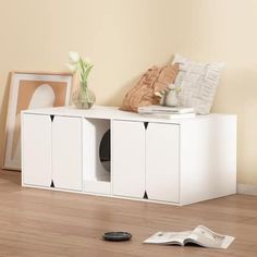 a white entertainment center sitting on top of a hard wood floor next to a vase with flowers