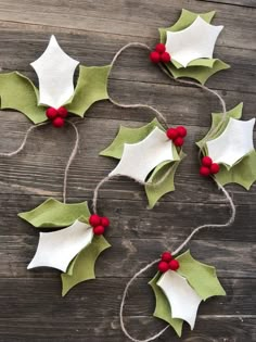 some holly leaves and red berries are hanging from twine on a wooden table with string