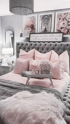 a bed with pink and grey sheets, pillows and fur rugs on top of it