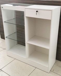 a white cabinet with glass doors on the top and bottom shelves in front of it