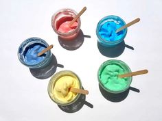 four different colored gels in small jars with wooden sticks sticking out of the lids