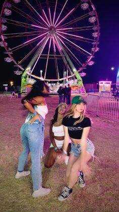 three girls standing in front of a ferris wheel