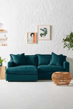 a living room with white walls and green furniture in the corner, including a large sectional couch