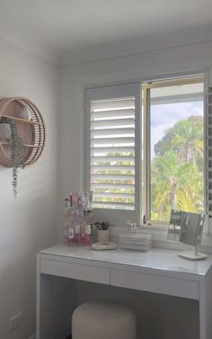 a white desk with a mirror, stool and window in the corner next to it