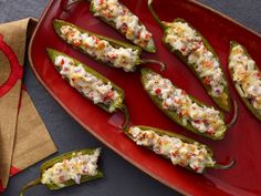 stuffed jalapenos on a red platter next to a napkin and cloth