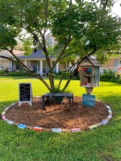 a small tree in the middle of a yard with some writing on it and a chalkboard sign