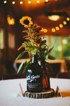 a beer bottle sitting on top of a table next to a vase filled with flowers