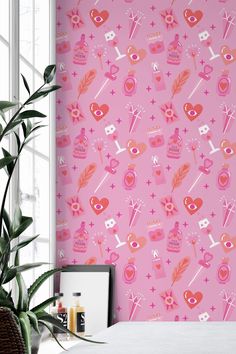 a pink wallpaper with hearts, arrows and other things on it is next to a potted plant