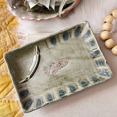 a decorative tray with fish on it next to beads