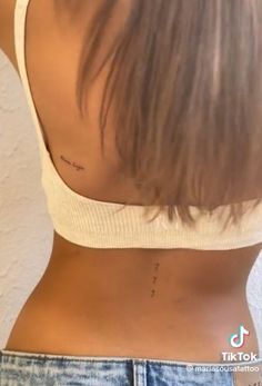 the back of a woman's stomach with small tattoos on her lower half and upper part