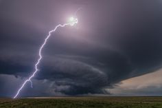 a lightning bolt is seen in the sky above an open field