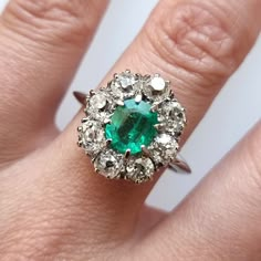 An incredible vintage cluster ring featuring an octagonal cut emerald, surrounded by eight old-cut diamonds, weighing an estimated total of 2.00 carats, claw set and mounted in 18ct white gold. A fantastic dress, statement or engagement ring from the 1940s to 1950s. Circa 1940-1950. Stamped and tested as 18ct gold. The estimated diamond colour is K-L. The estimated diamond clarity is Si1. The estimated total diamond weight is 2.00ct. The emerald measures approximately 7.65mm x 6.2mm x 4.00mm. Th Vintage Emerald Cut Gemstone Cluster Ring, Vintage Emerald Cut Cluster Ring With Gemstone, Vintage Emerald Cut Cluster Ring, Vintage Green Diamond Cluster Ring, Vintage Emerald Cluster Ring With Prong Setting, Vintage Cluster Ring, Fantastic Dress, Antique Ring Box, Emerald Ring Vintage