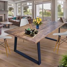 a dining room table with chairs and a potted plant on the center piece, in front of a fireplace