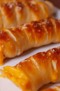 three croissants on a white plate with orange sauce and cheese in the middle