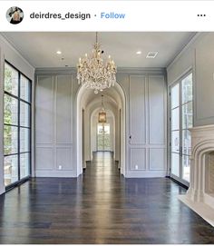 an empty hallway with chandelier and fireplace in the center, surrounded by large windows