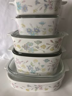 four dishes stacked on top of each other with flowers painted on the lids and bottom