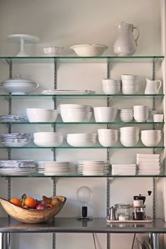 a shelf filled with lots of white plates and bowls on top of metal shelving