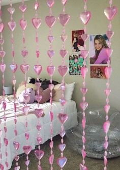 some pink hearts hanging from the ceiling in a room with a bed and pictures on the wall