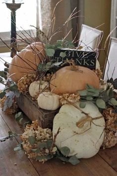 an arrangement of pumpkins and gourds on a table