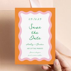 a person holding up a card with the words save the date written on it in green and pink