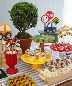 a table topped with lots of desserts next to a potted plant and tree