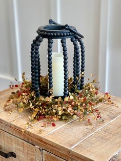 a candle that is sitting on top of a wooden table next to some leaves and berries