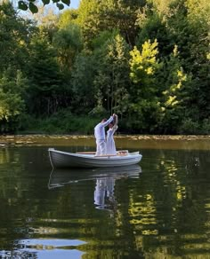 a man and woman in a boat on the water with trees in the back ground