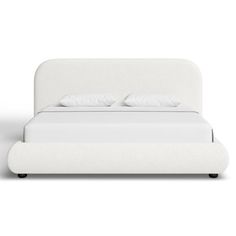 a white bed with two pillows on top of it