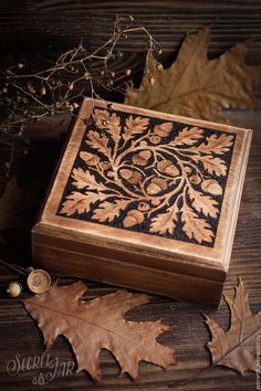 a wooden box sitting on top of a table next to leaves and acorns