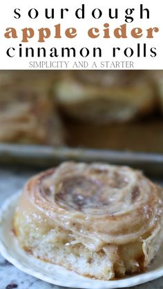 an apple cider cinnamon roll on a plate with text overlay that reads sourdough apple cider cinnamon rolls