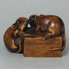 a bronze figurine of two dogs cuddling on top of a wooden box