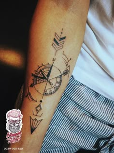 a person with a tattoo on their arm that has an arrow and compass on it