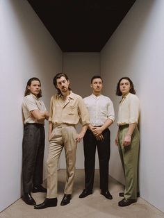 four men standing in an empty room with their arms crossed and looking at the camera