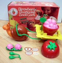 the toy strawberry shortcake snail car is next to its box and toys on the table