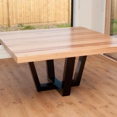 a wooden table sitting on top of a hard wood floor next to a sliding glass door