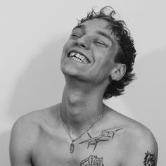 a shirtless man with tattoos on his chest smiling and looking up at the sky