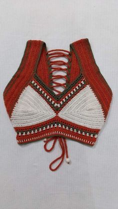 a red and white bralet with laces on the bottom, sitting on a white surface