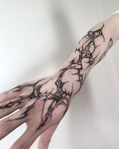 a person's hand with black ink on it and an abstract tree tattoo design