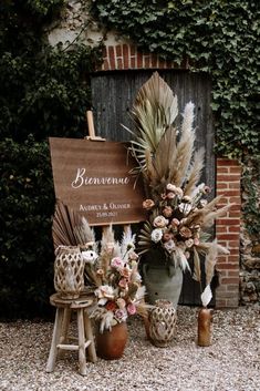 a wooden sign sitting on top of a table next to potted plants and flowers