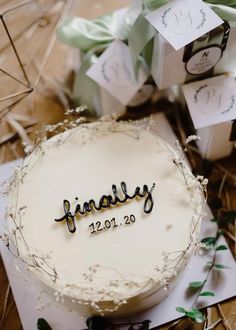 a white cake with writing on it sitting on top of a table next to presents