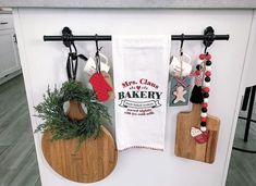 three wooden cutting boards with christmas decorations hanging from them on a kitchen wall next to an oven